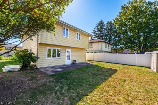 a view of backyard of house with wooden deck and large trees