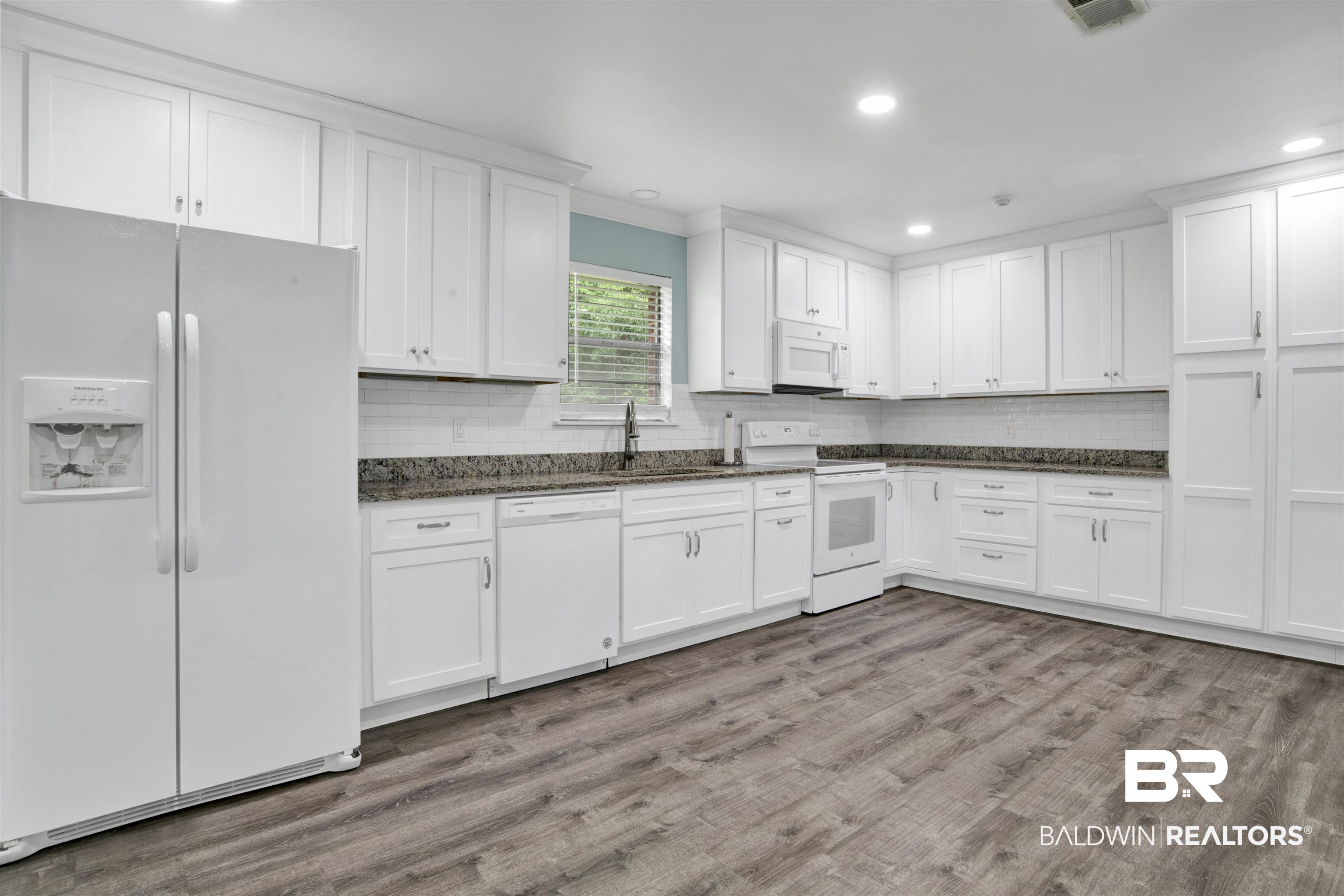 17714 Horseneck Road Bay Minette, AL 36507 - Photo 17 of 36 Kitchen featuring extensive white cabinetry, granite-style countertops, and wood-finish flooring