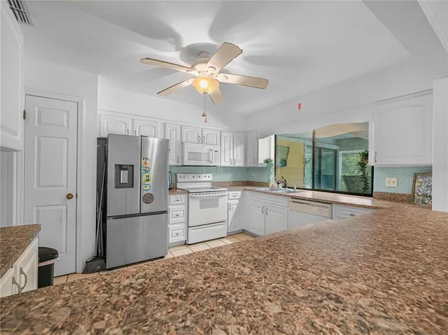 a kitchen with stainless steel appliances kitchen island granite countertop a refrigerator and microwave