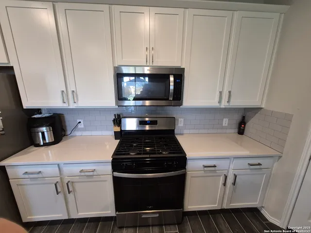 a kitchen with a stove and white cabinets