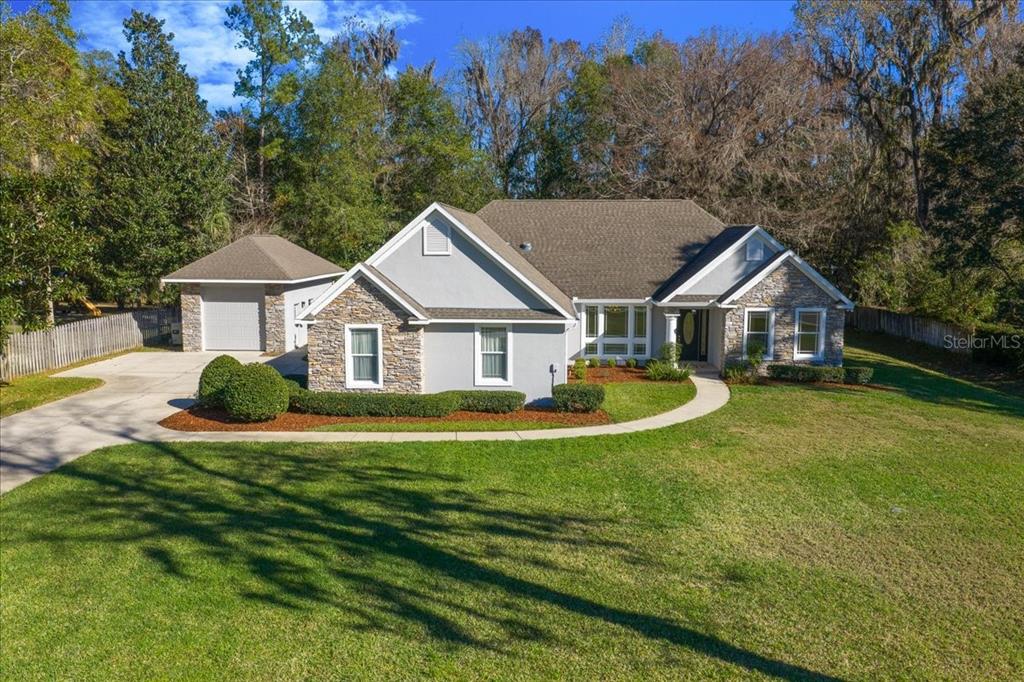 a view of a house with a big yard and large trees