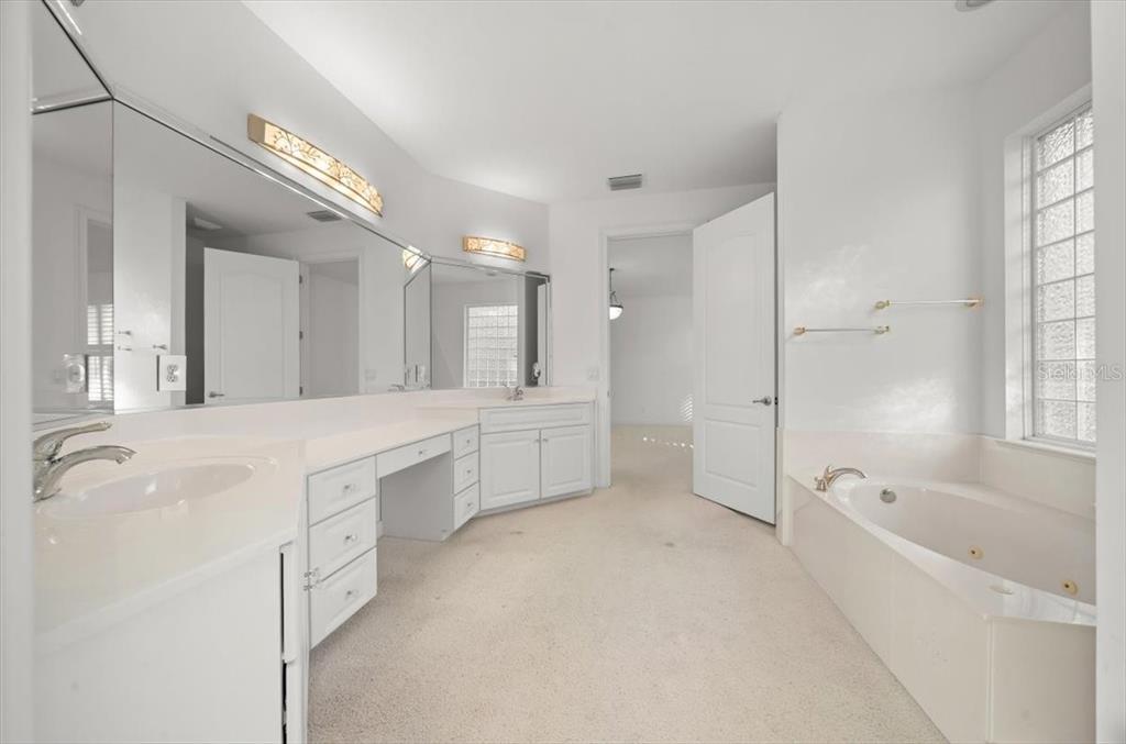 4929 Southwest 2nd Court Ocala, FL 34471 - Photo 24 of 60 a large white bathroom with a granite countertop sink a mirror and a bathtub