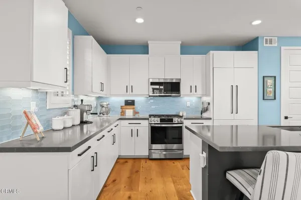 a kitchen with stainless steel appliances granite countertop a sink stove refrigerator and white cabinets
