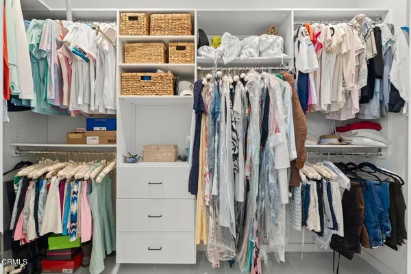 a view of walk in closet with clothes and shoes
