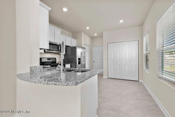 a kitchen with kitchen island granite countertop a stove a sink a refrigerator and white cabinets with wooden floor