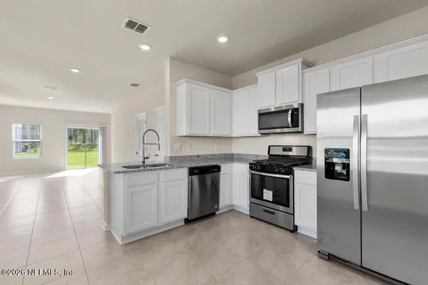 a kitchen with stainless steel appliances granite countertop a stove a sink and a refrigerator