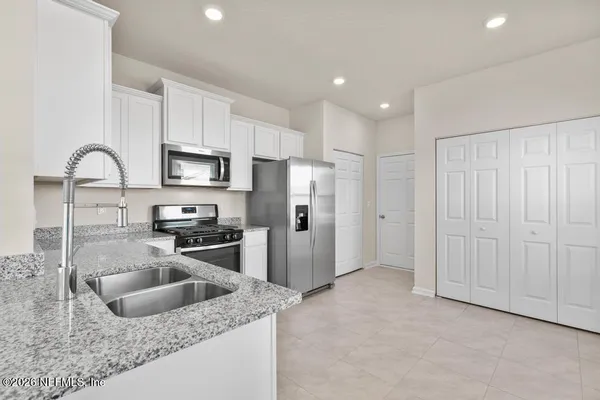 a kitchen with stainless steel appliances granite countertop a refrigerator a stove a sink a microwave and white cabinets