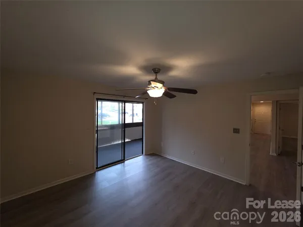 a view of an empty room with a window and wooden floor