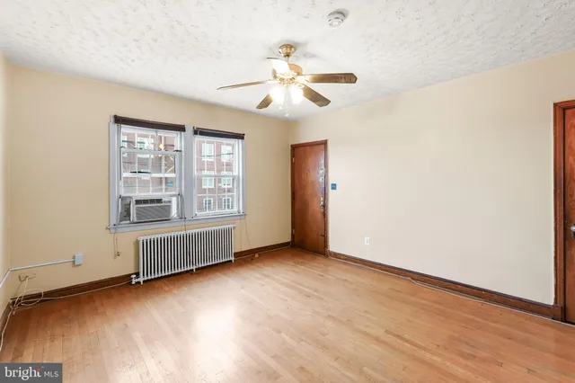 an empty room with wooden floor chandelier fan and windows