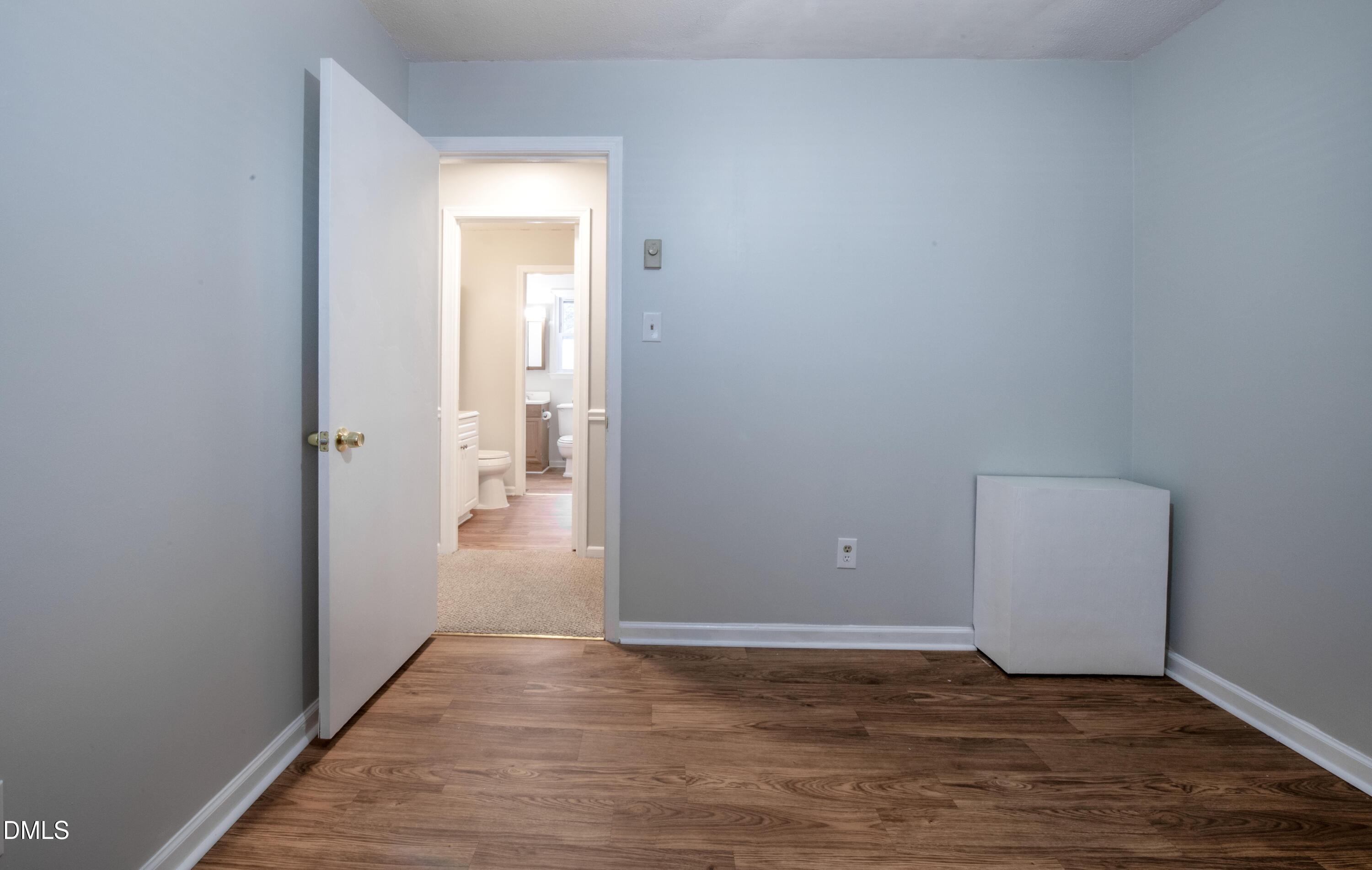 116 East Judd Street Zebulon, NC 27597 - Photo 18 of 21 a view of an empty room with wooden floor and a bathroom