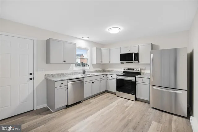 a kitchen with granite countertop stainless steel appliances a refrigerator sink and microwave