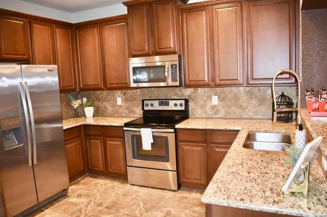 a kitchen with stainless steel appliances granite countertop a refrigerator stove and sink