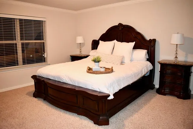 a large bed sitting in a bedroom next to a lamp and a window