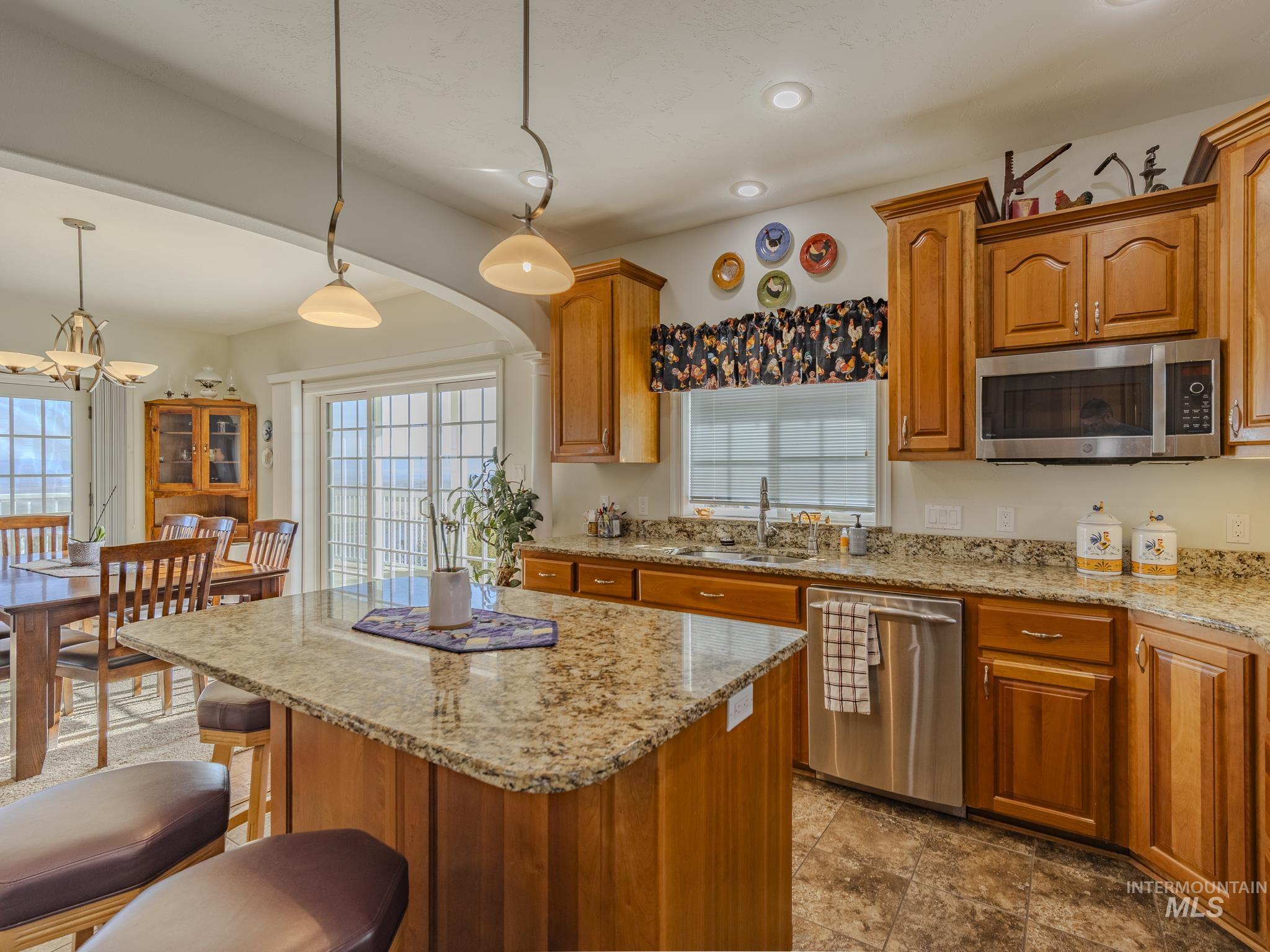659 Reservation Line Road Cottonwood, ID 83522 - Photo 13 of 50 Kitchen featuring light stone counters, stainless steel appliances, a kitchen breakfast bar, wood finish cabinets, and a kitchen island