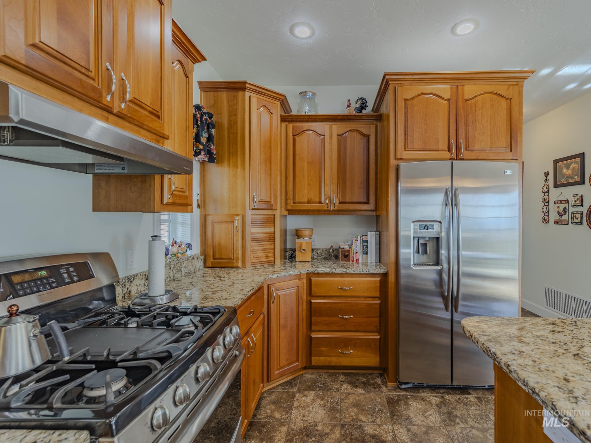 659 Reservation Line Road Cottonwood, ID 83522 - Photo 14 of 50 Kitchen with stainless steel appliances, light stone counters, and wood finish cabinetry