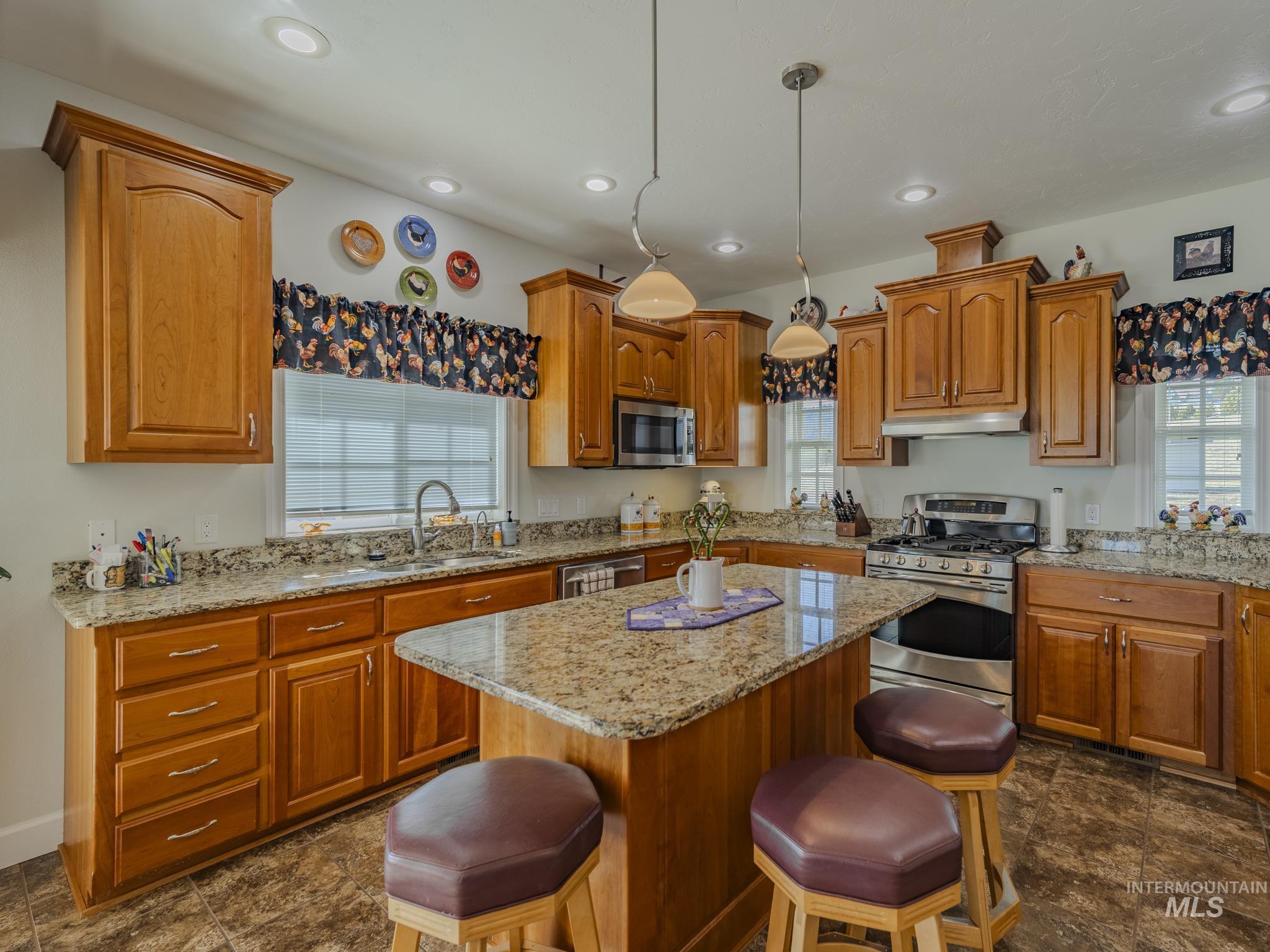 659 Reservation Line Road Cottonwood, ID 83522 - Photo 15 of 50 Kitchen featuring stainless steel appliances, hanging light fixtures, light stone counters, and a kitchen bar