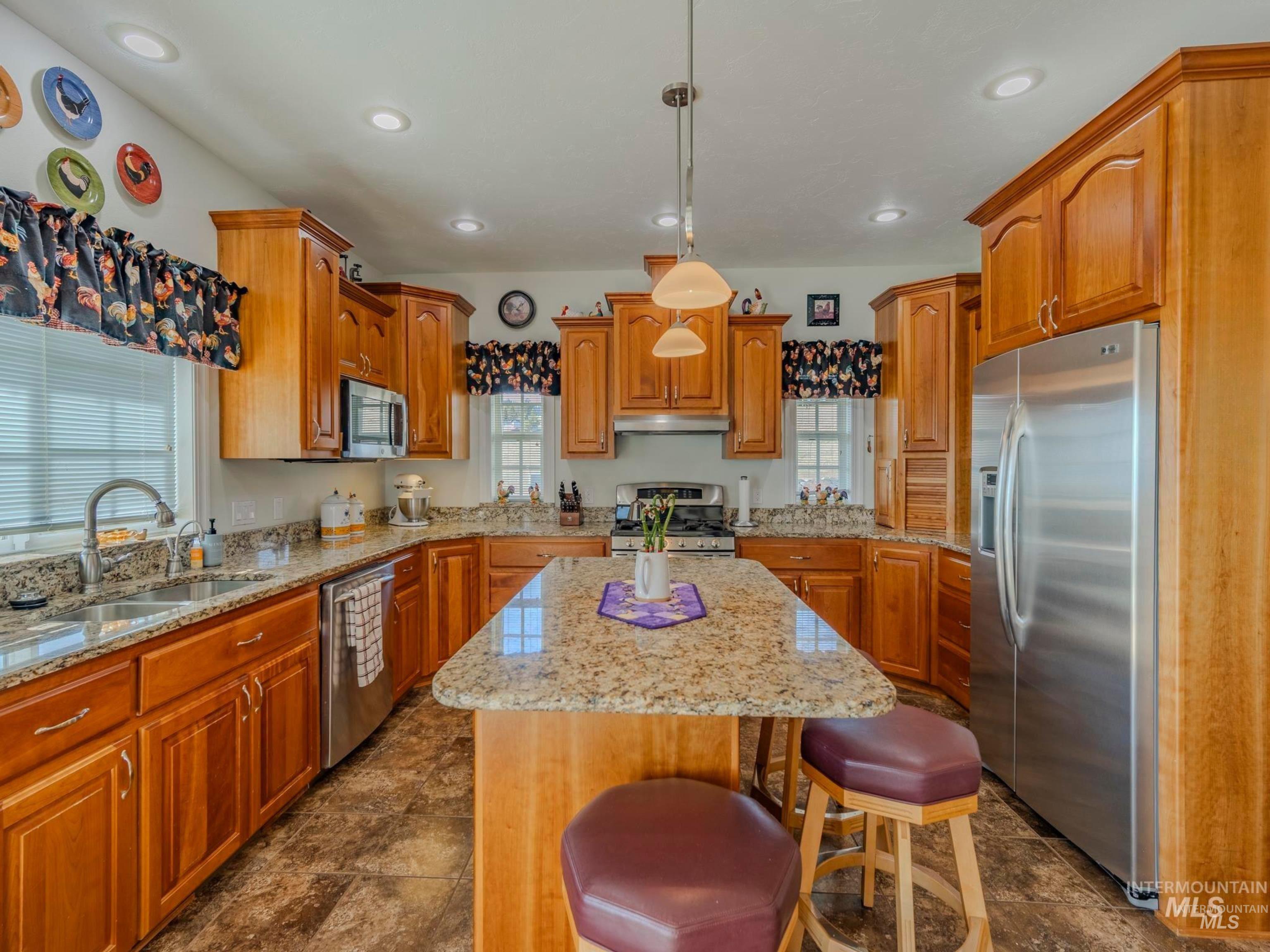 659 Reservation Line Road Cottonwood, ID 83522 - Photo 17 of 50 Kitchen with stainless steel appliances, a breakfast bar area, light stone countertops, a kitchen island, and wood finish cabinets