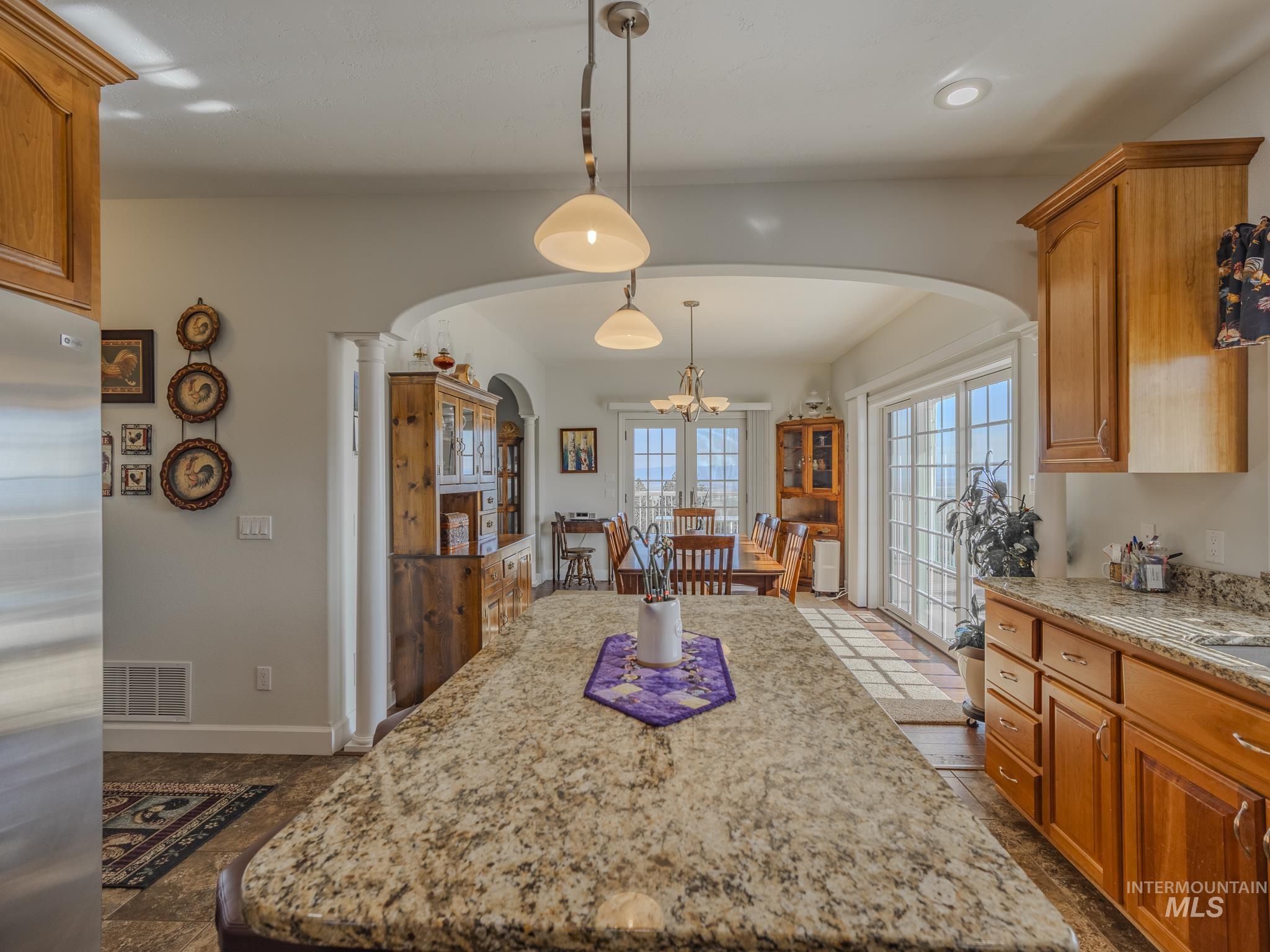 659 Reservation Line Road Cottonwood, ID 83522 - Photo 18 of 50 Kitchen featuring stainless steel refrigerator, wood finish cabinetry, light stone counters, and a kitchen island