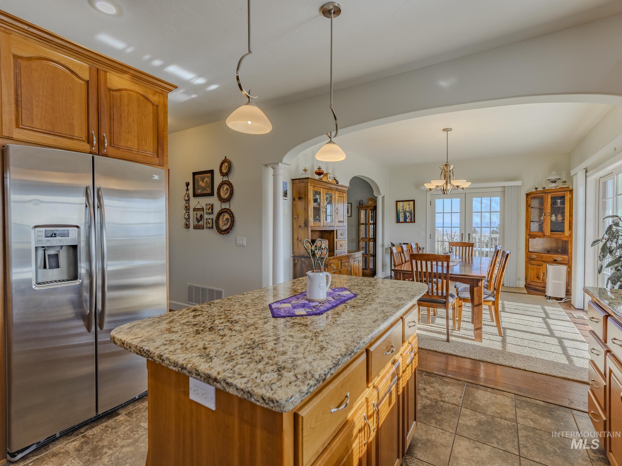 659 Reservation Line Road Cottonwood, ID 83522 - Photo 19 of 50 Kitchen featuring stainless steel refrigerator with ice dispenser, wood finish cabinetry, light stone countertops, and a kitchen island