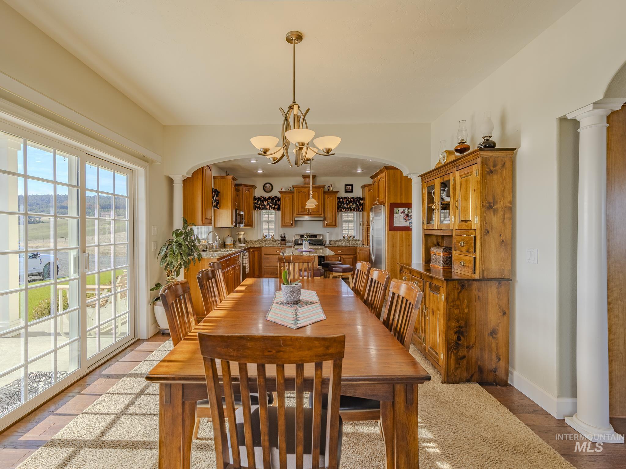 659 Reservation Line Road Cottonwood, ID 83522 - Photo 21 of 50 Dining area with decorative columns, arched walkways, suspended lighting, and light wood finished floors
