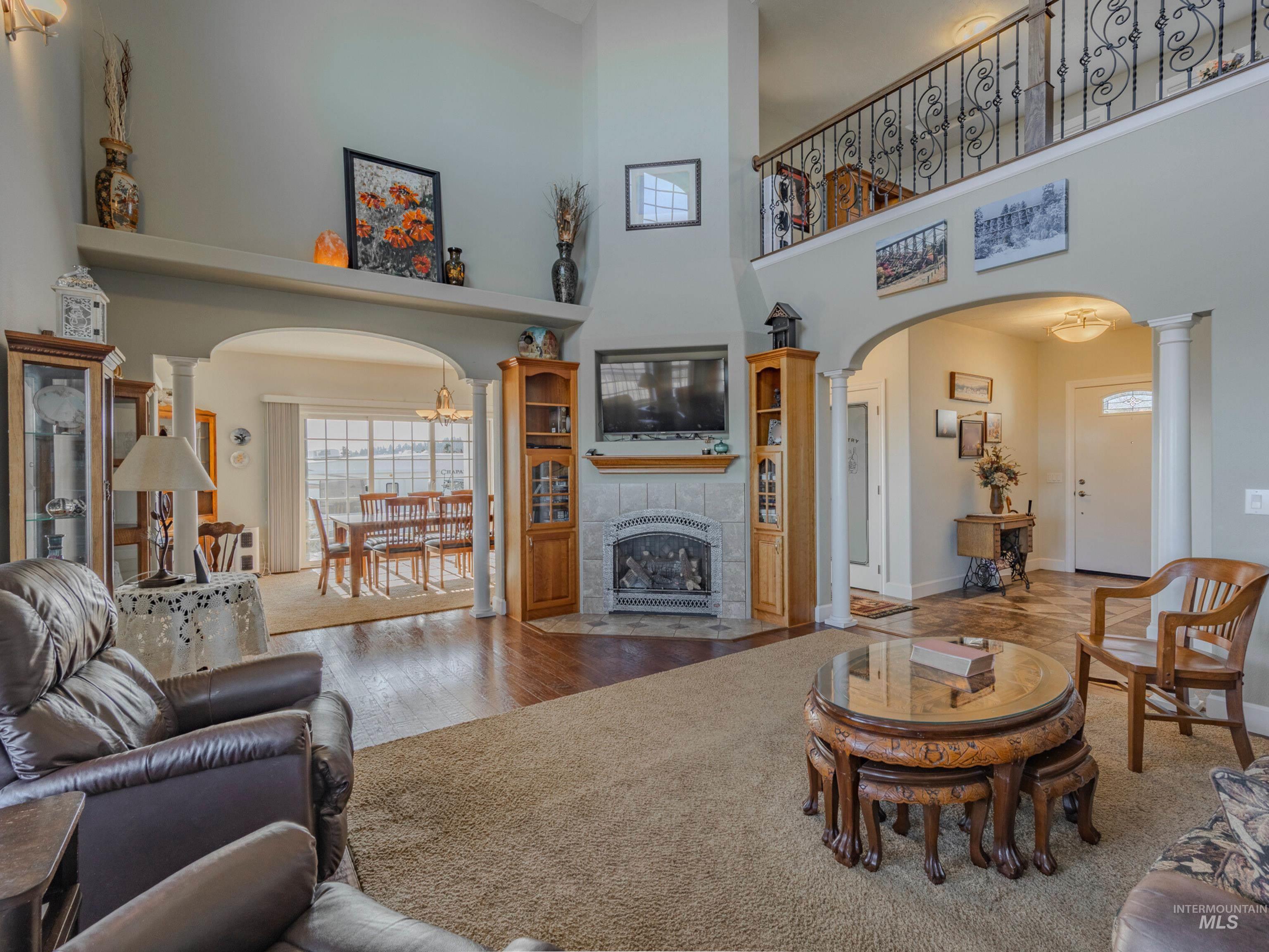 659 Reservation Line Road Cottonwood, ID 83522 - Photo 8 of 50 Living room featuring arched walkways, hardwood / wood-style flooring, a high ceiling, a fireplace, and ornate columns