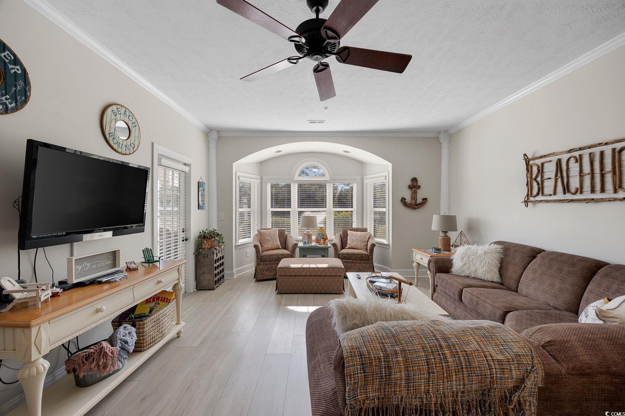 121 Waypoint Ridge Avenue, Unit P8 Little River, SC 29566 - Photo 11 of 40 Living room featuring light wood-style floors, crown molding, ceiling fan, and a textured ceiling