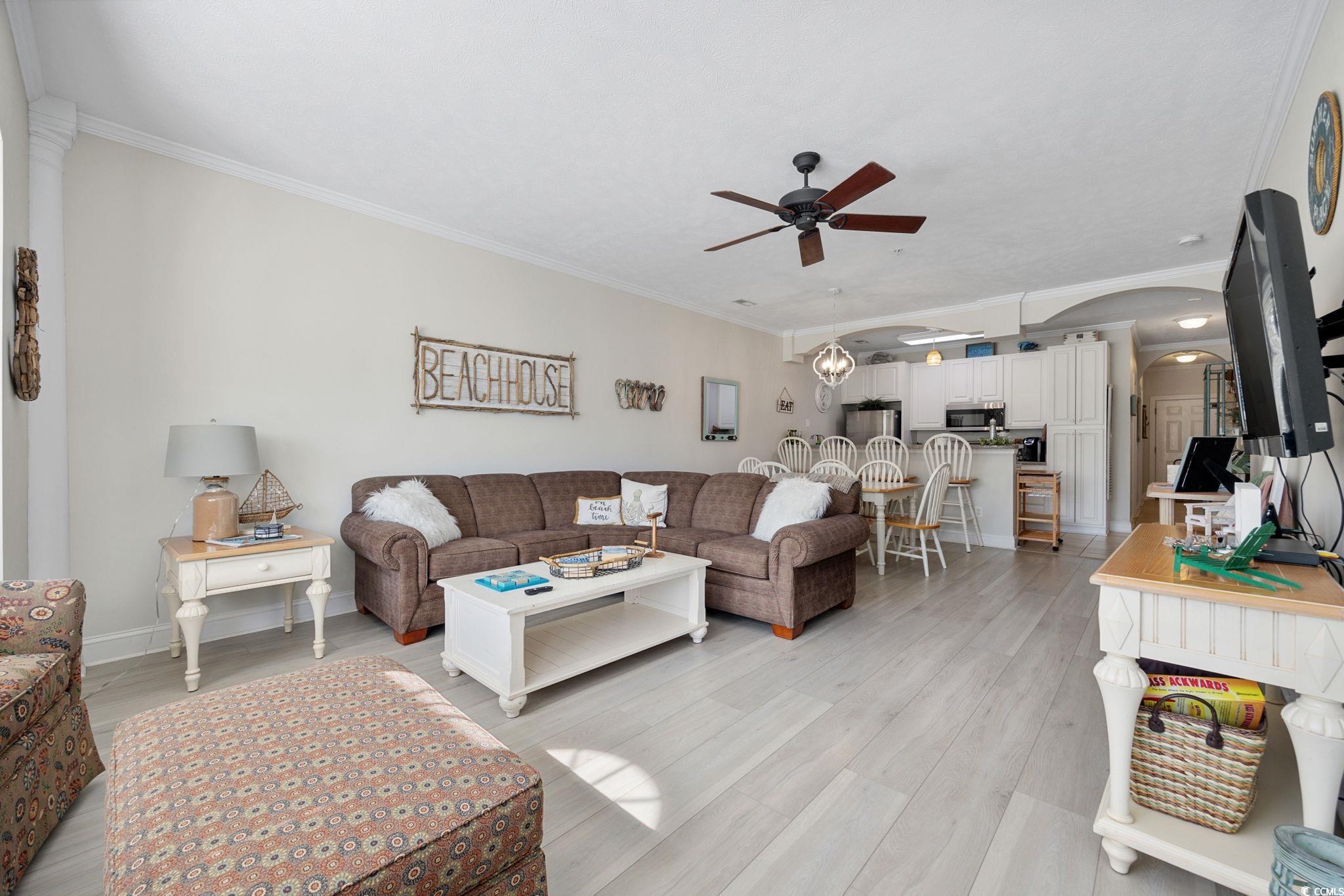 121 Waypoint Ridge Avenue, Unit P8 Little River, SC 29566 - Photo 12 of 40 Living area featuring arched walkways, ornamental molding, light wood-style flooring, a ceiling fan, and a chandelier