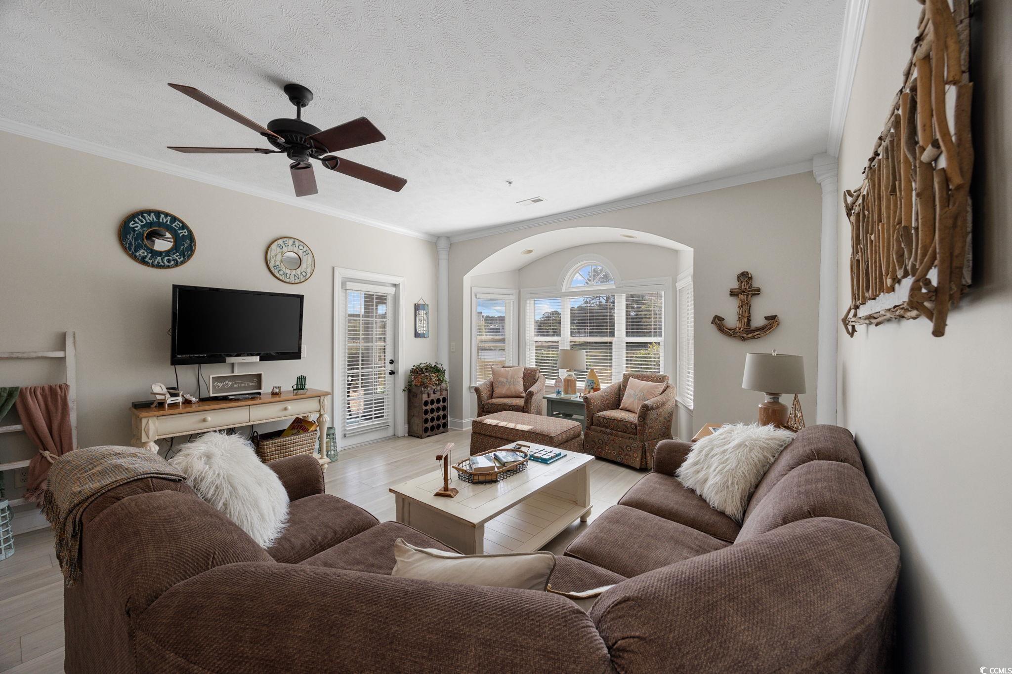 121 Waypoint Ridge Avenue, Unit P8 Little River, SC 29566 - Photo 14 of 40 Living room with crown molding, a textured ceiling, ceiling fan, wood finished floors, and arched walkways