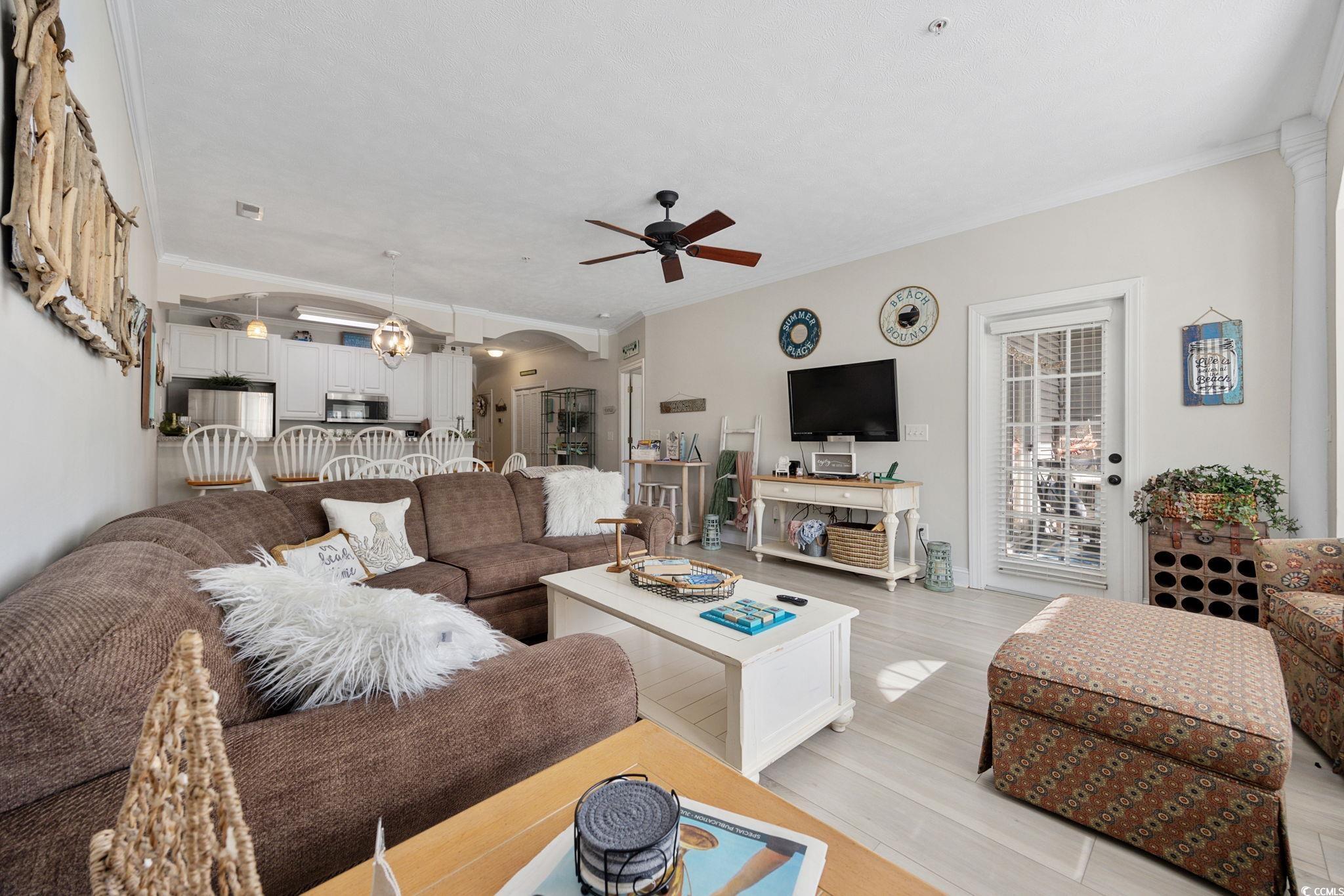 121 Waypoint Ridge Avenue, Unit P8 Little River, SC 29566 - Photo 15 of 40 Living area featuring crown molding, arched walkways, wood finished floors, and a ceiling fan