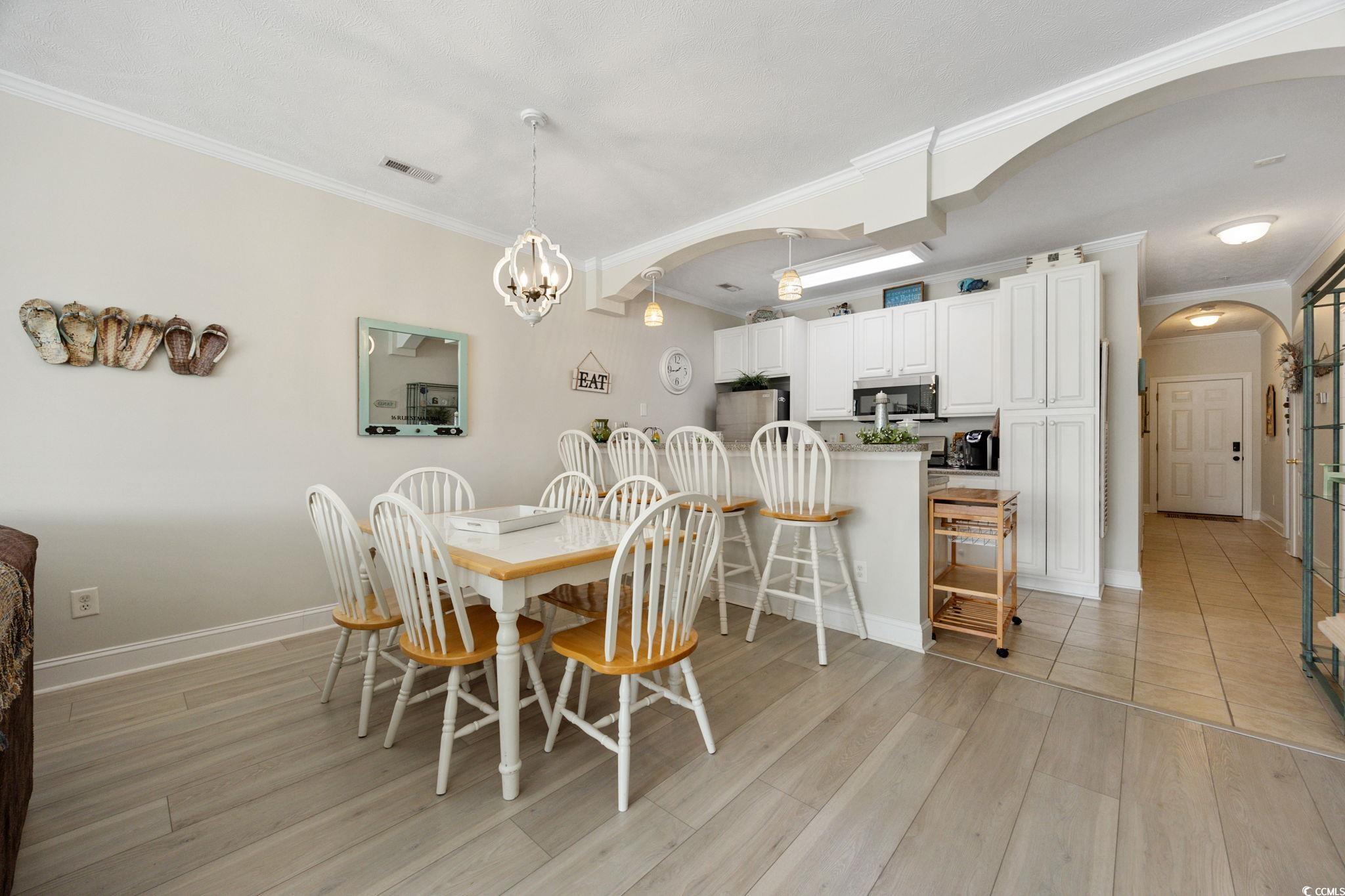 121 Waypoint Ridge Avenue, Unit P8 Little River, SC 29566 - Photo 4 of 40 Dining space with arched walkways, light wood finished floors, ornamental molding, and a chandelier