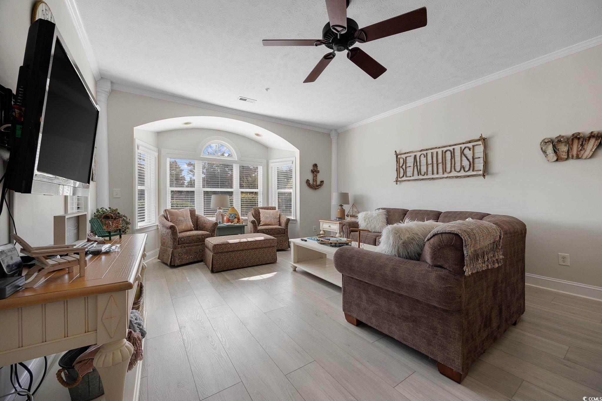 121 Waypoint Ridge Avenue, Unit P8 Little River, SC 29566 - Photo 10 of 40 Living area featuring crown molding, light wood finished floors, and a ceiling fan