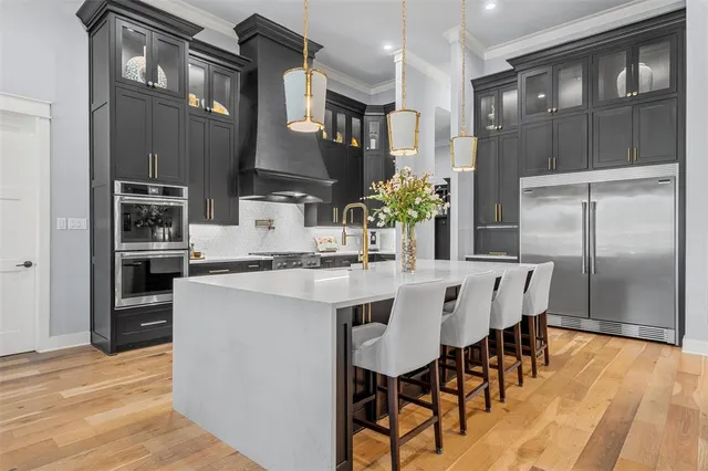 a kitchen with stainless steel appliances kitchen island granite countertop a dining table chairs and a refrigerator