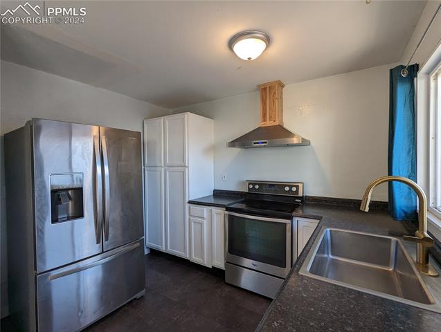 209 Kiva Road Colorado Springs, CO 80911 - Photo 5 of 6 The Updated Kitchen offers a vinyl floor, white cabinets, and stainless steel appliances including a smooth top range oven, vent hood, dishwasher, and French door refrigerator.