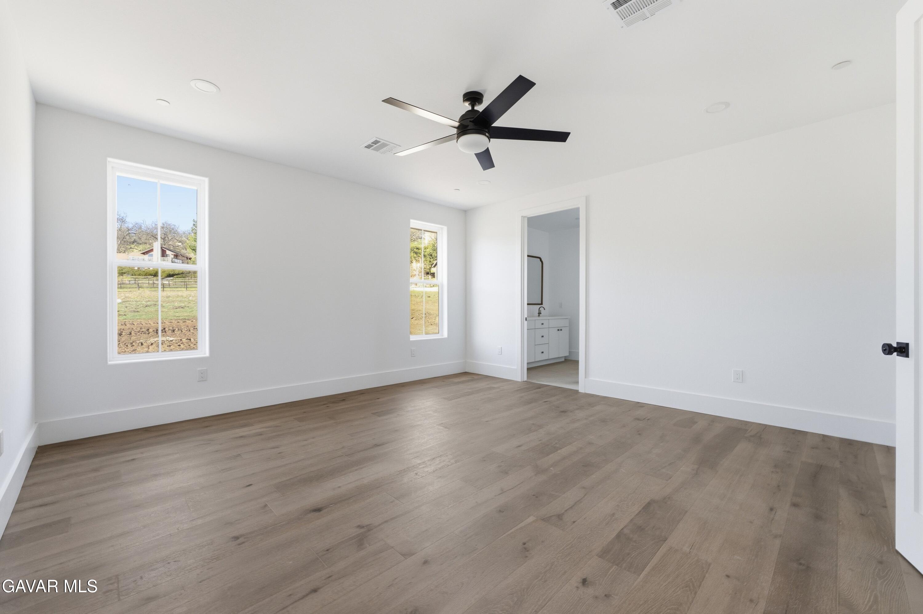 24401 Oaktree Court Tehachapi, CA 93561 - Photo 19 of 36 an empty room with wooden floor a ceiling fan and windows
