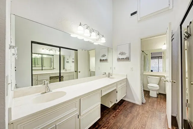 a spacious bathroom with a double vanity sink a mirror and a toilet