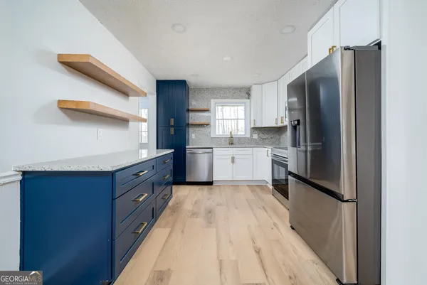 a kitchen with stainless steel appliances granite countertop a refrigerator a sink a stove and oven
