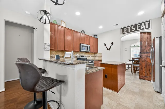 a kitchen with granite countertop wooden cabinets a dining table and chairs