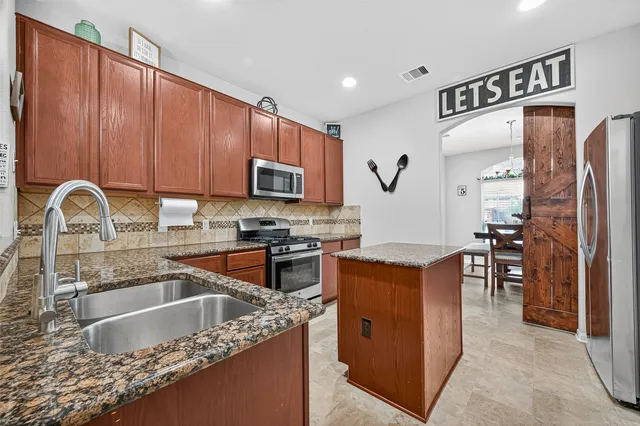 a kitchen with stainless steel appliances granite countertop a sink stove and refrigerator
