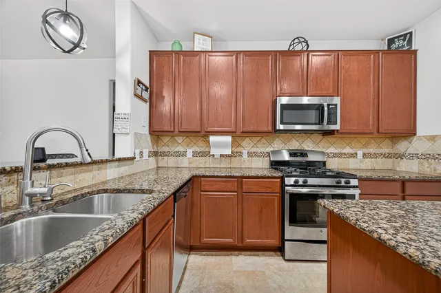 a kitchen with granite countertop a sink stainless steel appliances and cabinets