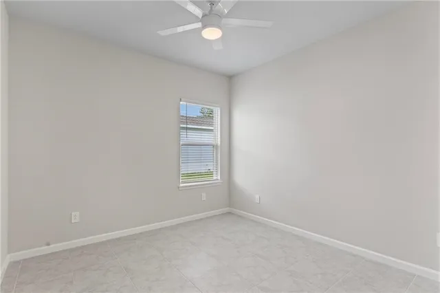 an empty room with chandelier fan and windows
