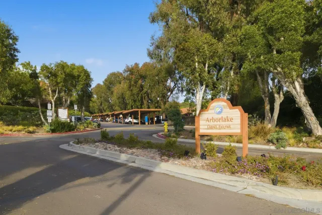 a view of a park that has a sign board large trees