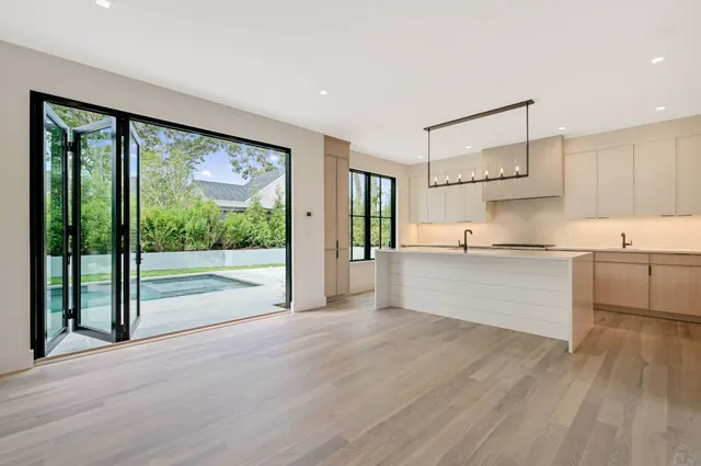 a living room with stainless steel appliances kitchen island hardwood floor and a window
