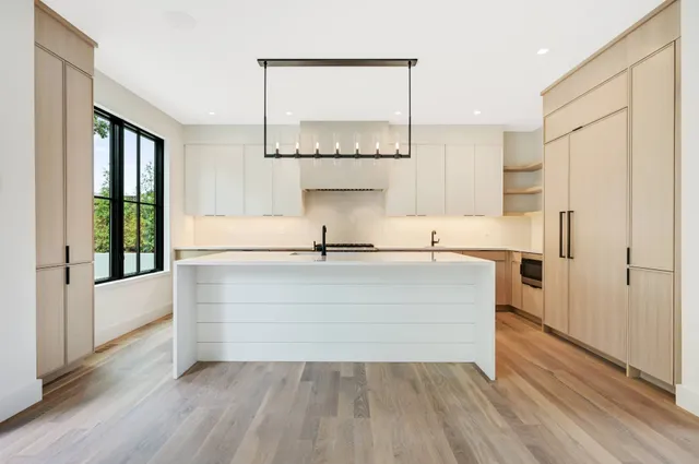 a kitchen with stainless steel appliances a large counter top a chandelier and a sink