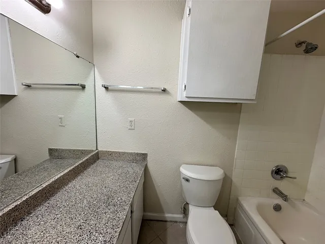 a bathroom with a granite countertop toilet and a sink