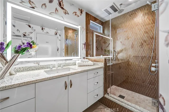 a bathroom with a granite countertop sink a mirror and a shower