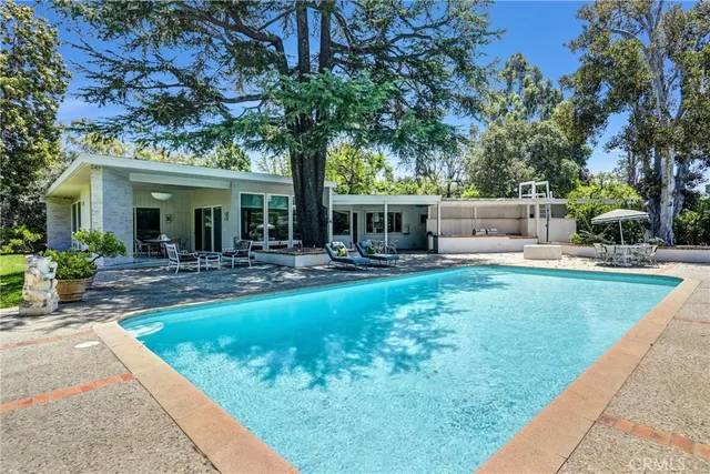 a view of house with swimming pool and sitting area