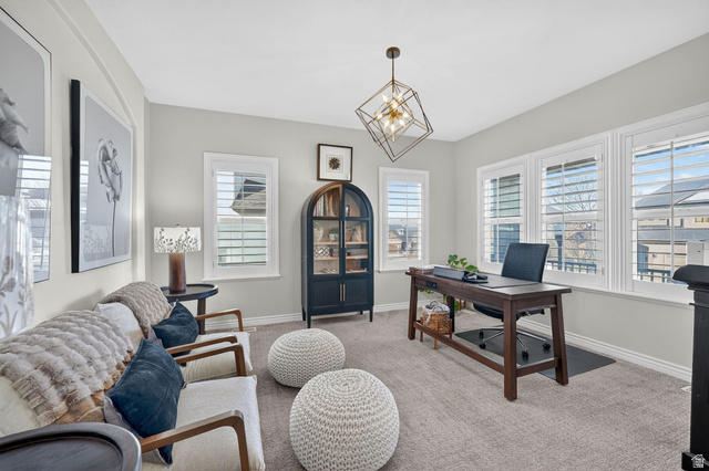 14738 Tangle Hill Road Herriman, UT 84096 - Photo 12 of 66 Light grey wall paint with white trim, featuring plantation shutters on multiple windows, a geometric bronze chandelier, and light grey carpeting