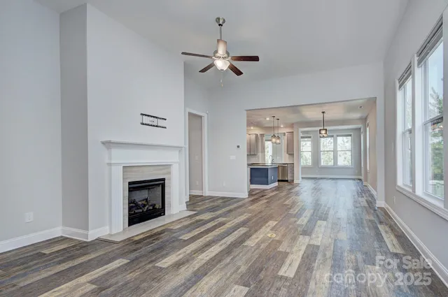 a view of an empty room with wooden floor fireplace and a window