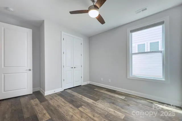 a view of empty room with wooden floor and fan