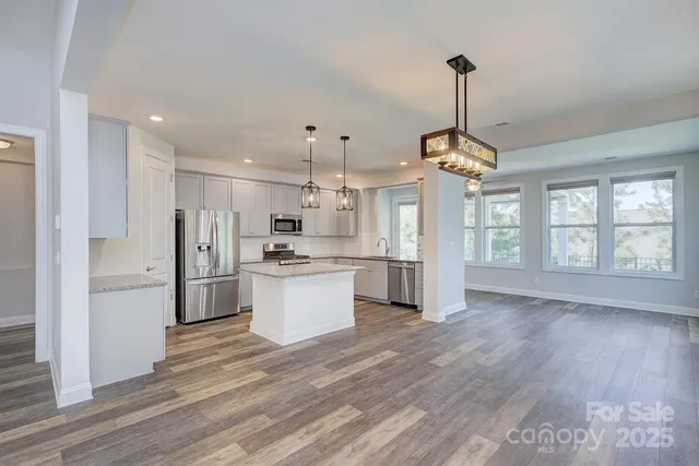 a view of a kitchen with refrigerator microwave and wooden floor